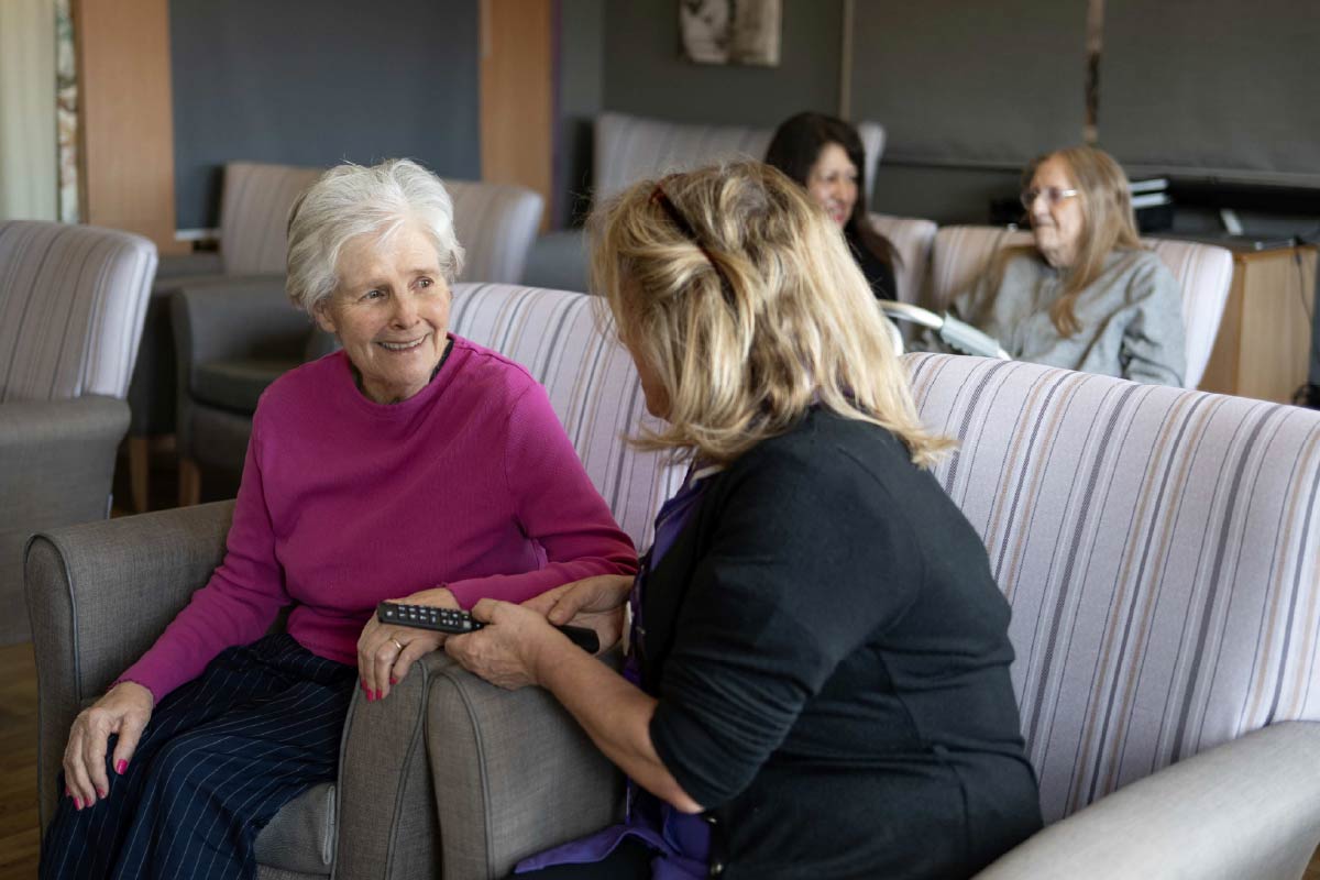 Avante Care and Support – Care Homes 004 Residents and Avante Carers sitting on lounge chairs talking and smiling